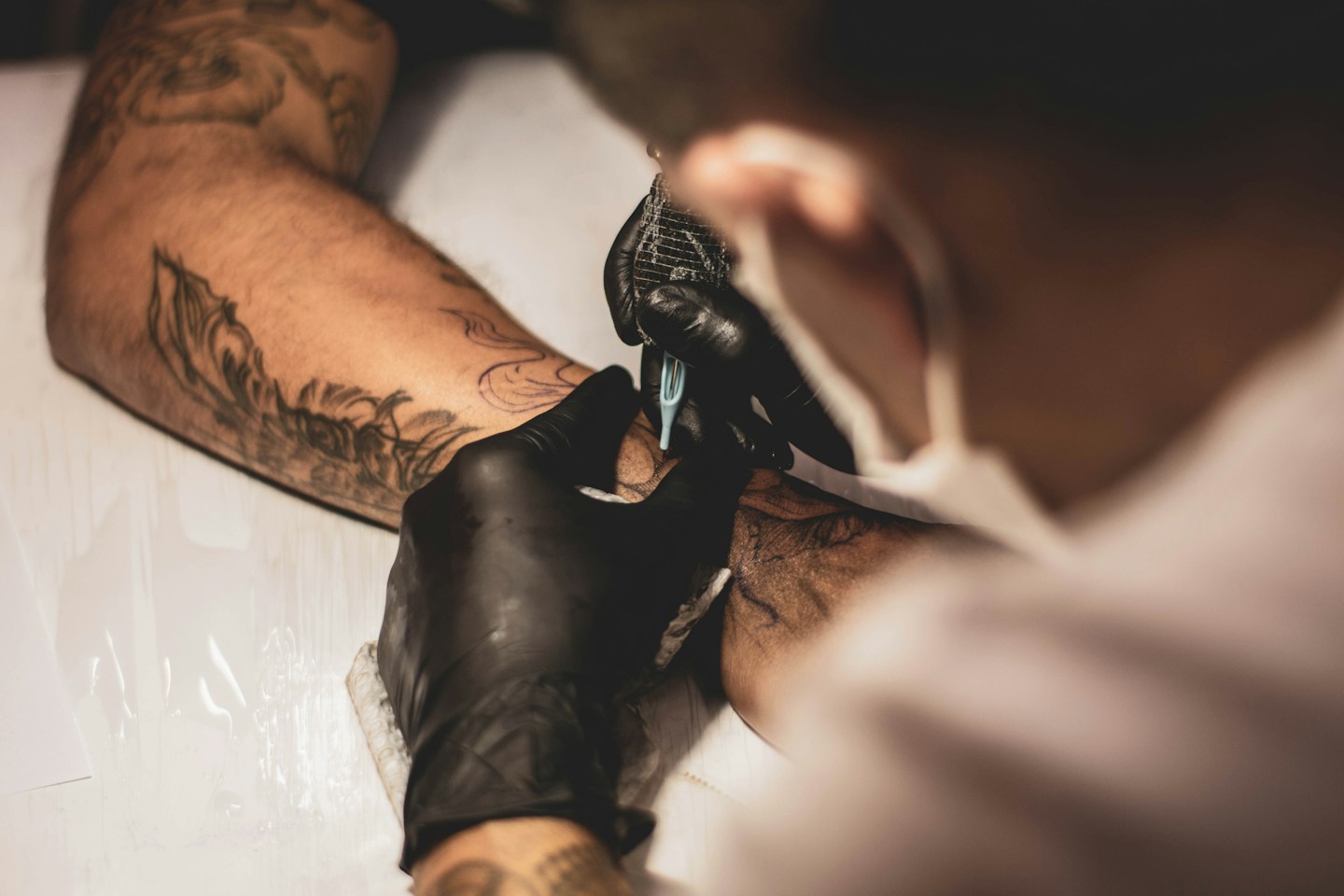 Tatuador a trabalhar num desenho no braço de uma pessoa